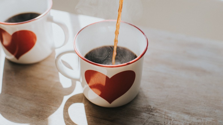 Coffee pouring into a mug with a red heart design