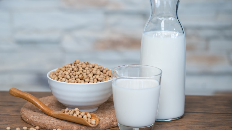 Soy milk next to soybeans on a table