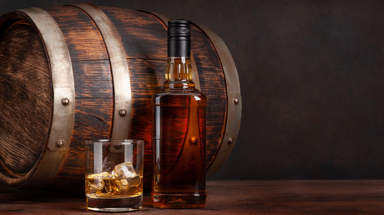 glass of bourbon, bottle, and barrel