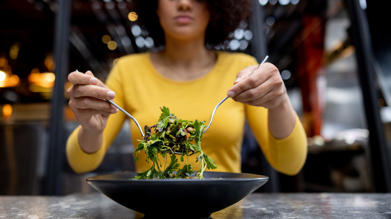 Woman lifting salad with forks