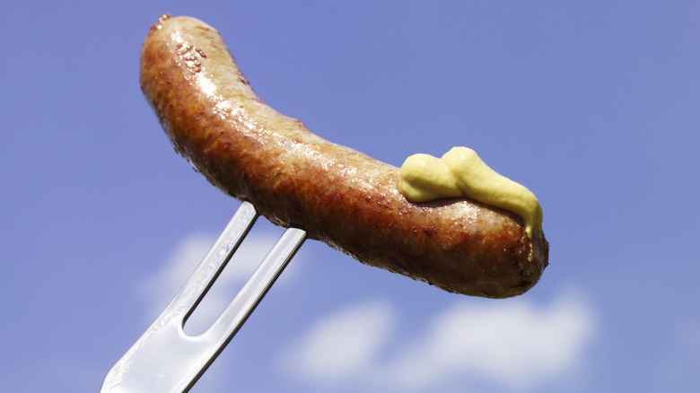 Bratwurst with mustard on fork