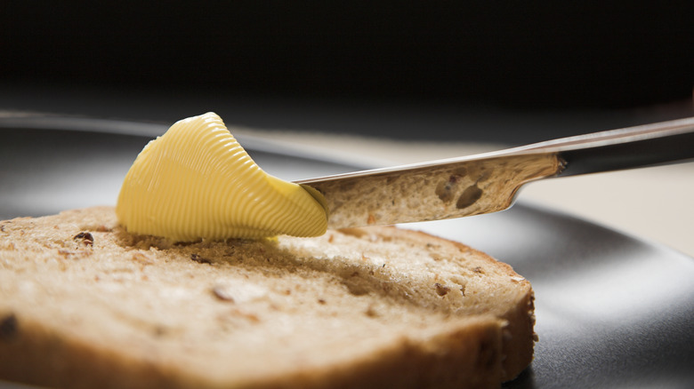 Close-up of a knife spreading butter on bread 