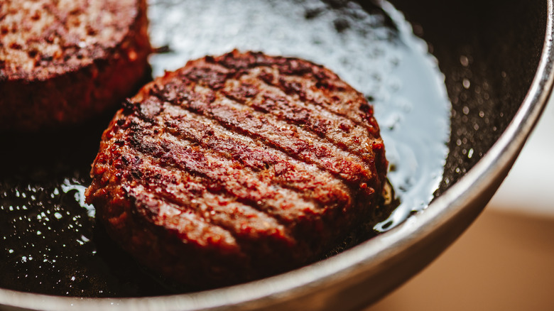 ground meat patty cooking in a pan