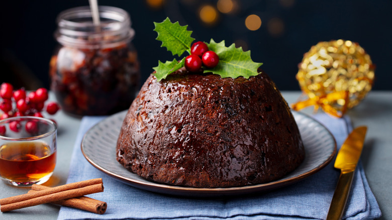 A Christmas pudding topped with holly on a festive table