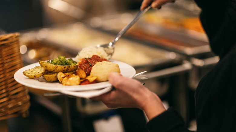 Diner dishing food onto a buffet plate