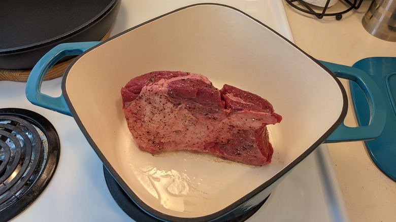 Raw blade steak about to be braised in a Dutch oven