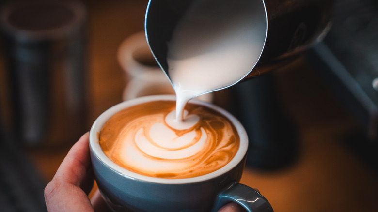 hand making milk art on cappuccino