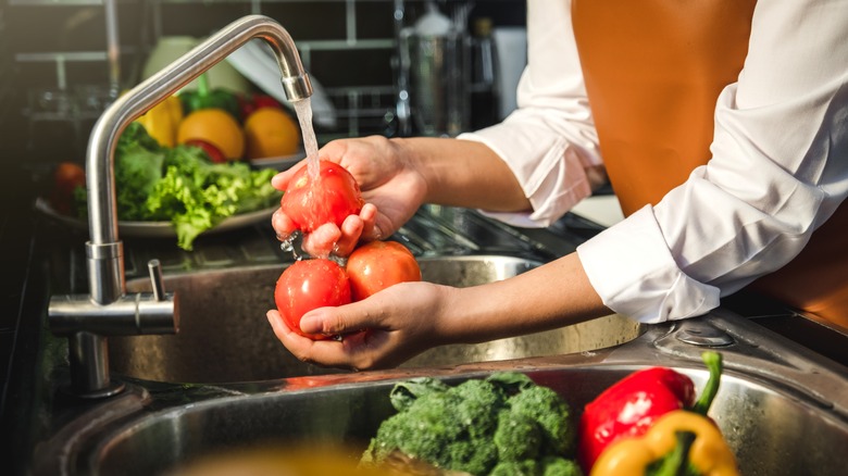 person washing tomatoes at sink