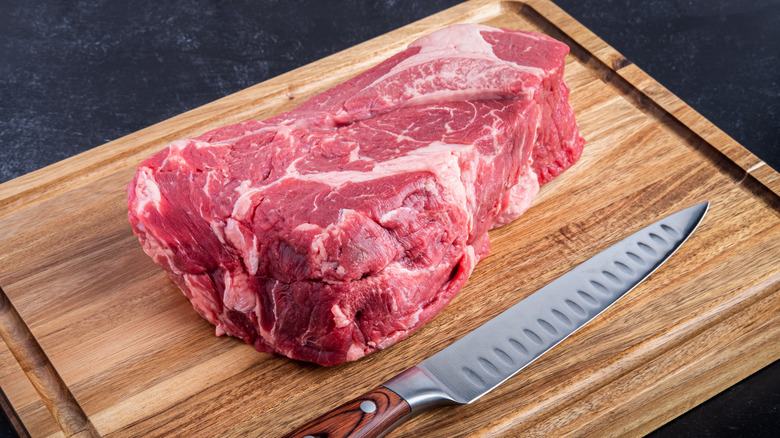 Beef chuck roast with knife on board