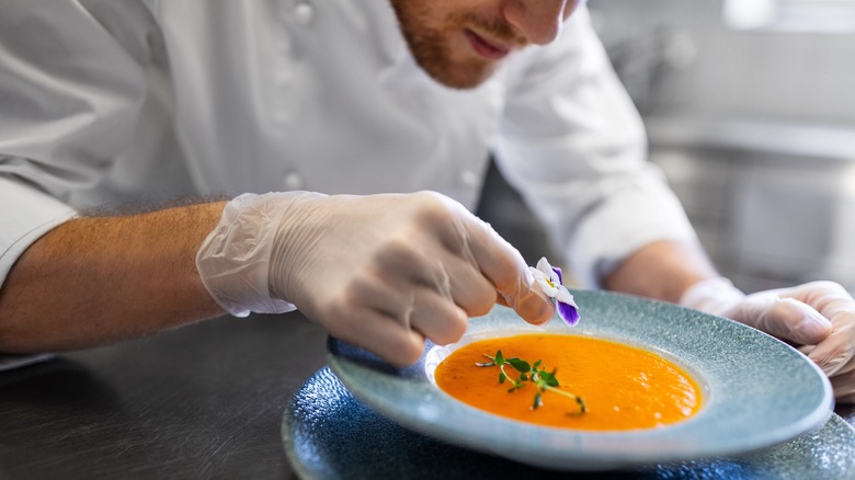 chef adding garnish to soup