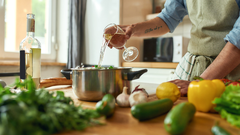 man deglazing pot with wine