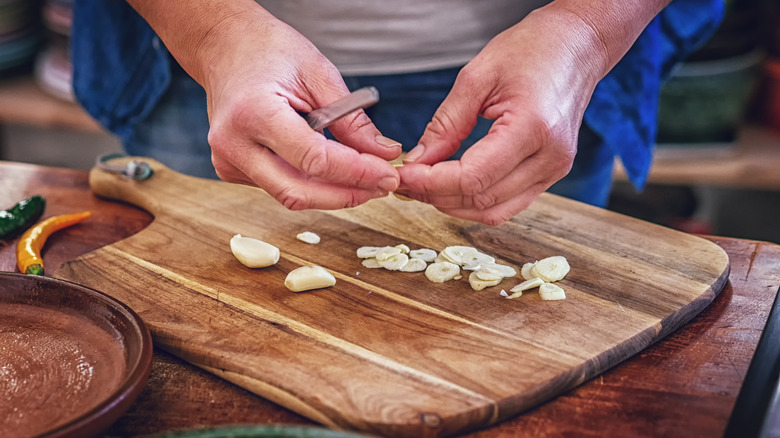 Hands separating garlic cloves on a cutting board