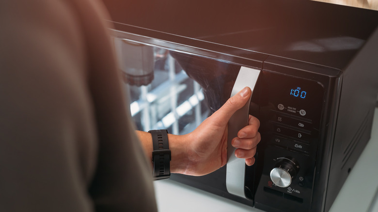 person holding microwave door handle