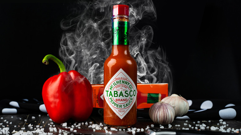 Tabasco sauce in a bottle with a pepper, garlic, and rock salt