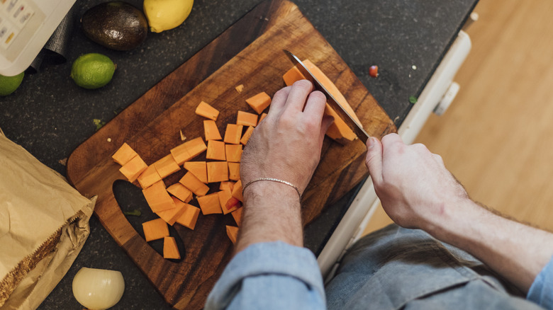 Hands cutting sweet potatoes 