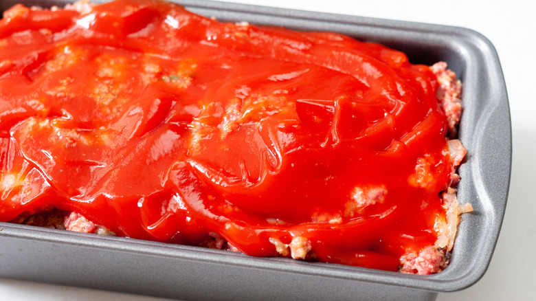 Meatloaf in loaf pan, covered in ketchup