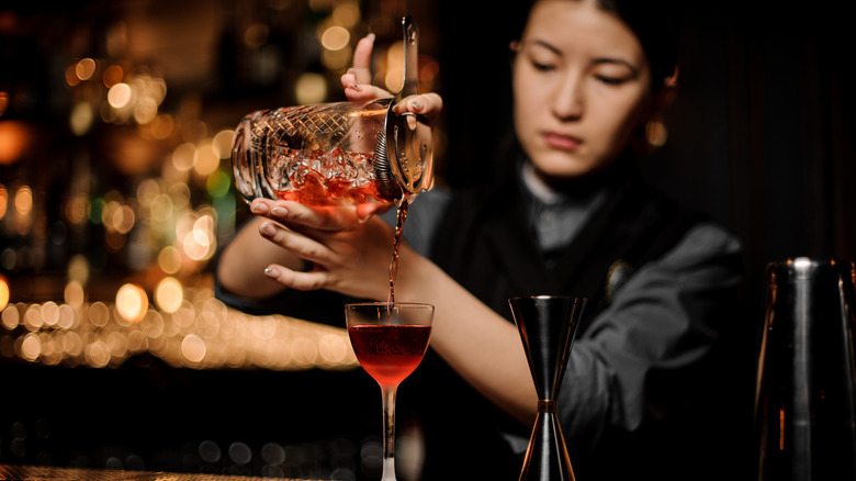 Bartender straining cocktail