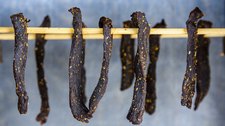 biltong drying on wooden sticks