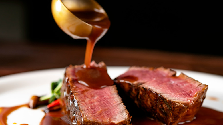 pouring steak sauce on steak