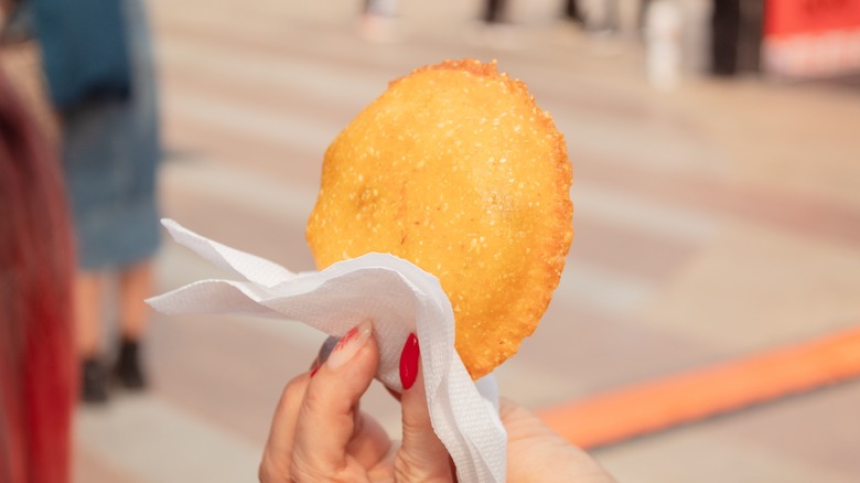 Person holding arepa on street