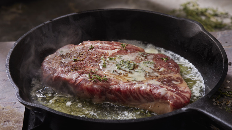 steak cooking in cast iron skillet