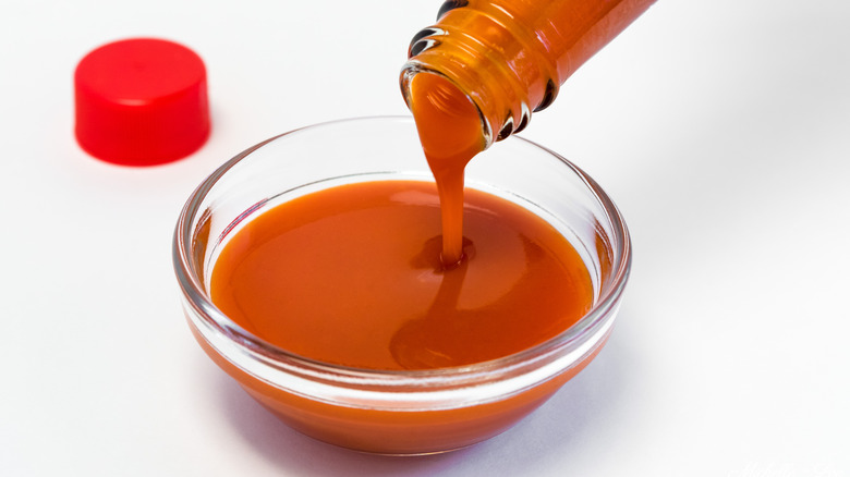 Hot sauce pouring into ramekin