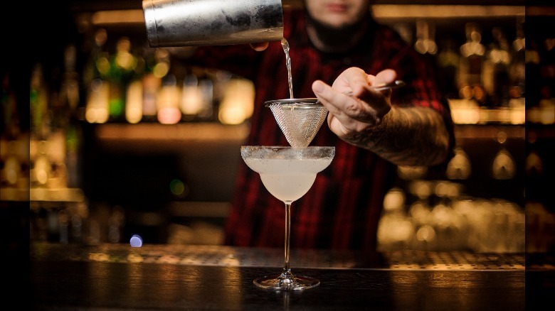 Bartender pouring a margarita into a glass