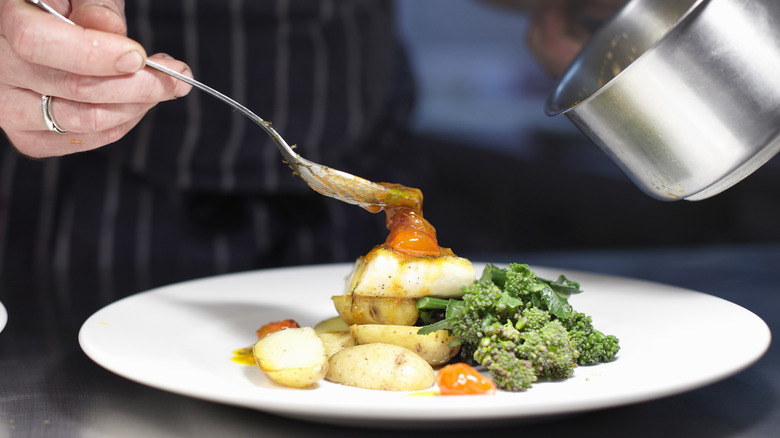 chef plating dish with sauce