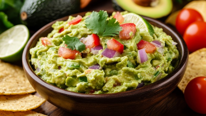 guacamole bowl with tomatoes, cilantro, onions, and chips