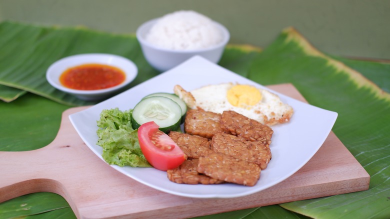 pan-fried tempeh steak with fried egg and hite rice on a white plate