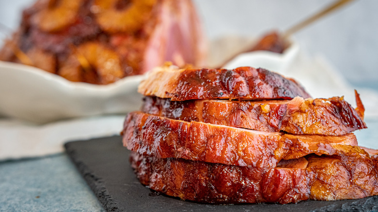 A smoked ham is sliced at a table