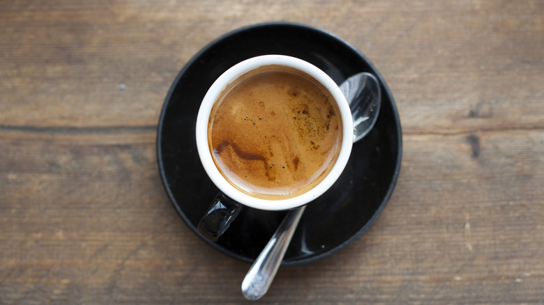 Overhead view of concentrated coffee in white cup with spoon on the side