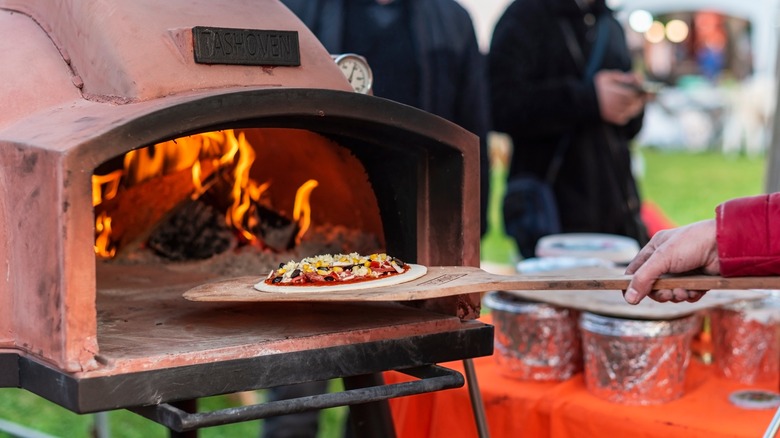 person using outdoor pizza oven