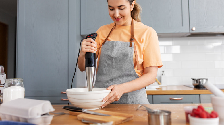 Person using immersion blender in bowl
