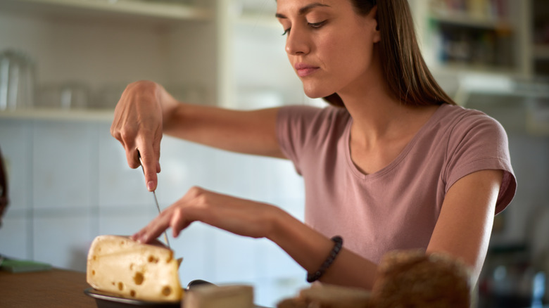 woman cutting a cheese block