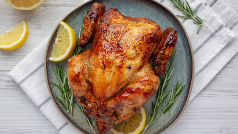 Rotisserie chicken plated with lemon and rosemary