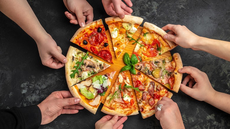 People grabbing multiple slices of pizza