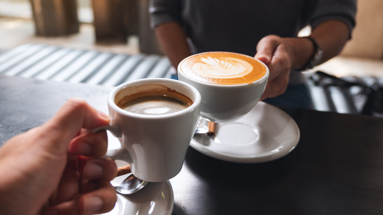 Two people clinking coffee mugs