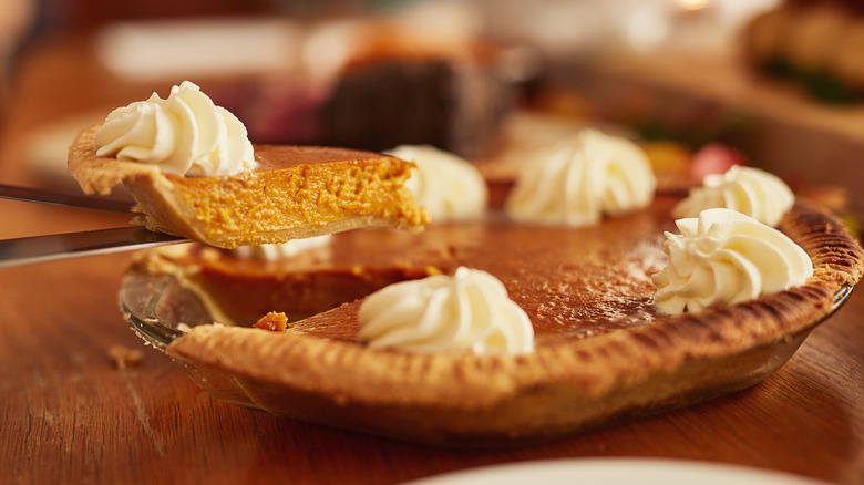 lifting a slice out of a pumpkin pie