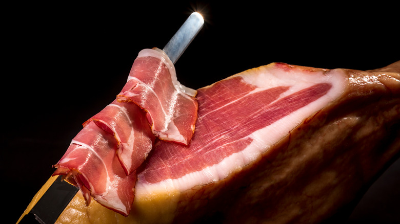 a knife slicing prosciutto 