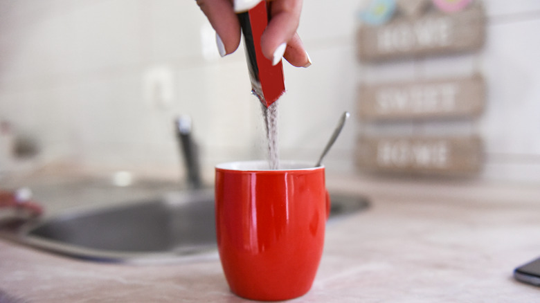 pouring instant coffee into mug