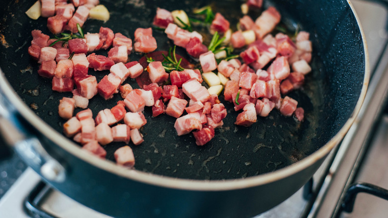 Cubed pancetta sauteeing in a skillet