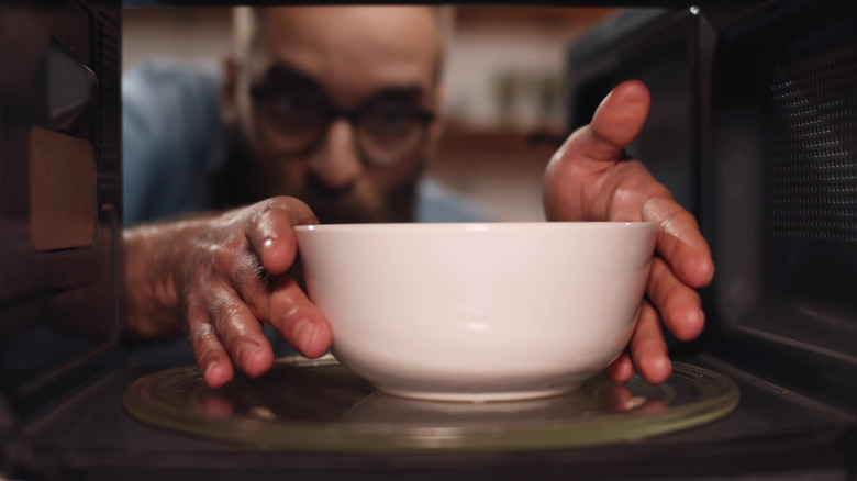 man grabbing bowl from microwave