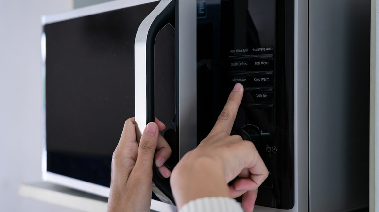 hands pushing microwave button