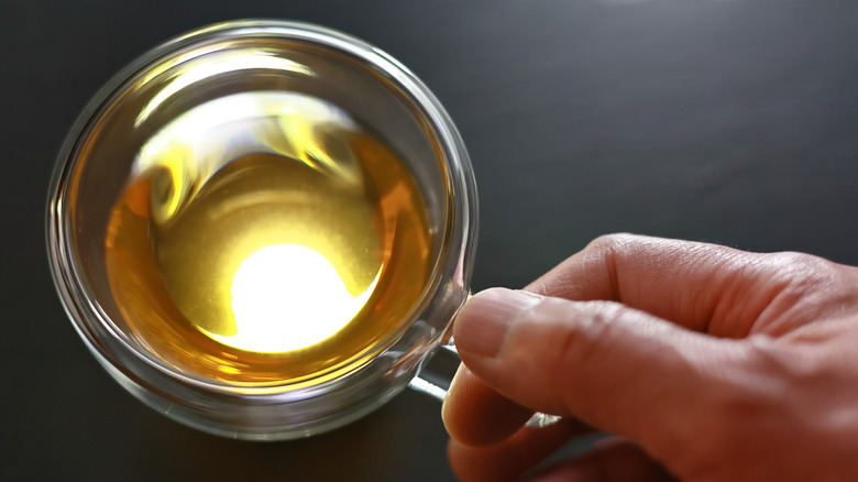 man holding cup of yellow tea