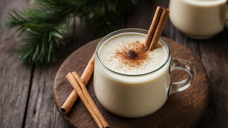 A cup of eggnog with cinnamon sticks