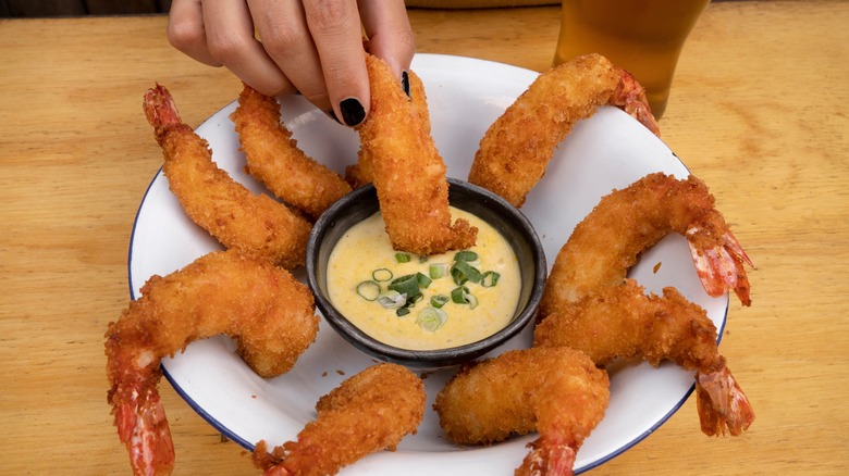 dipping fried shrimp into sauce