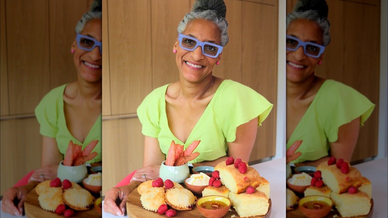 Carla Hall smiling behind tray of food 