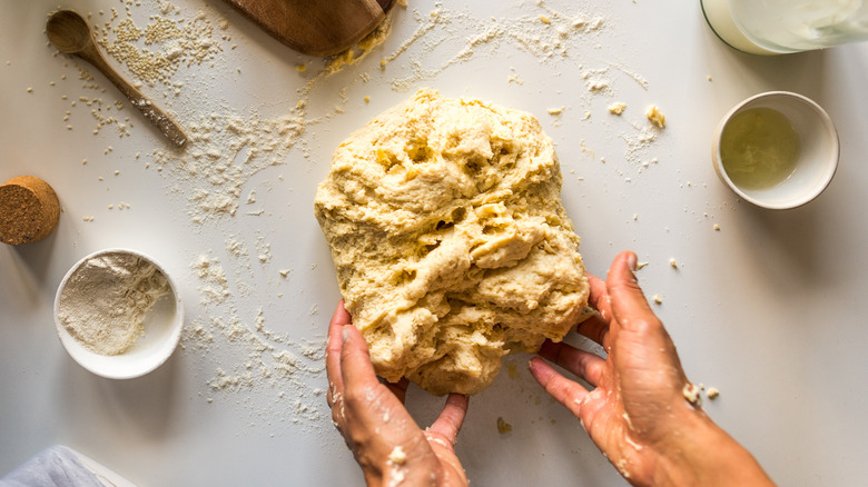 Hands kneading dough surrounded by ingredients