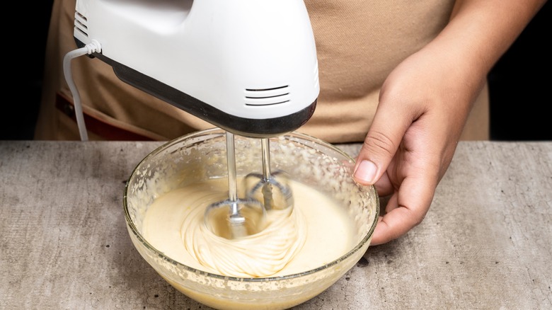 Person using hand mixer with a bowl of batter